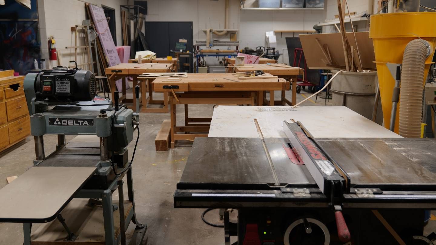 multiple workspaces with machinery and wood in a studio setting