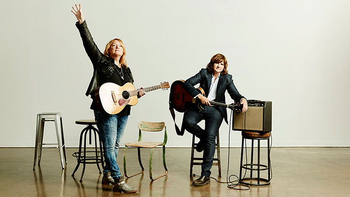 Indigo Girls standing on a stage holding guitars