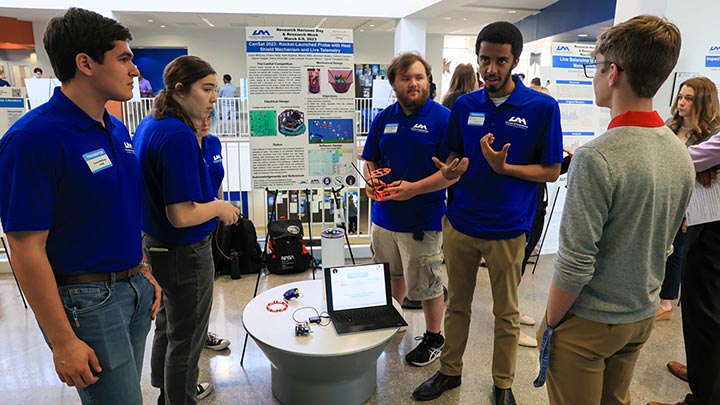 a UAH student presents a research poster to a small audience ?>