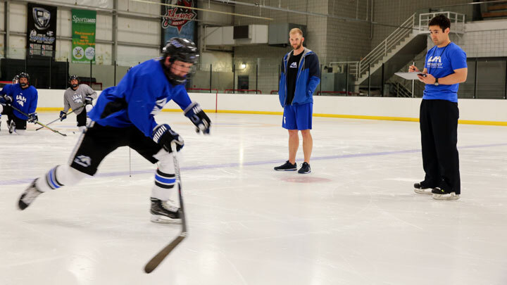 Hockey player on the ice monitored by a coach.