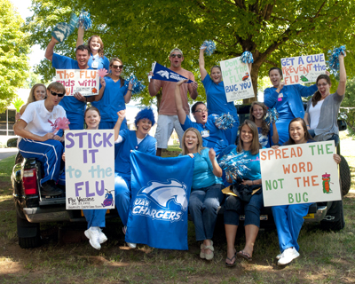 A group of nursing students hold up signs promoting vacination against the flu.