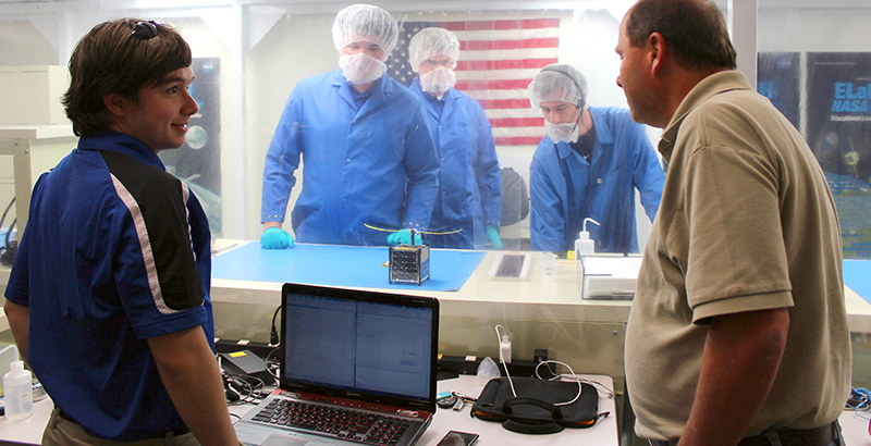 From left, University of Alabama in Huntsville (UAH) Space Hardware Club members Matt Rodencal, Eric Becnel and Mason Manning review ChargerSat 1 in California with a California Polytechnic State University representative and a NASA Kennedy Space Center Launch Services Program representative.