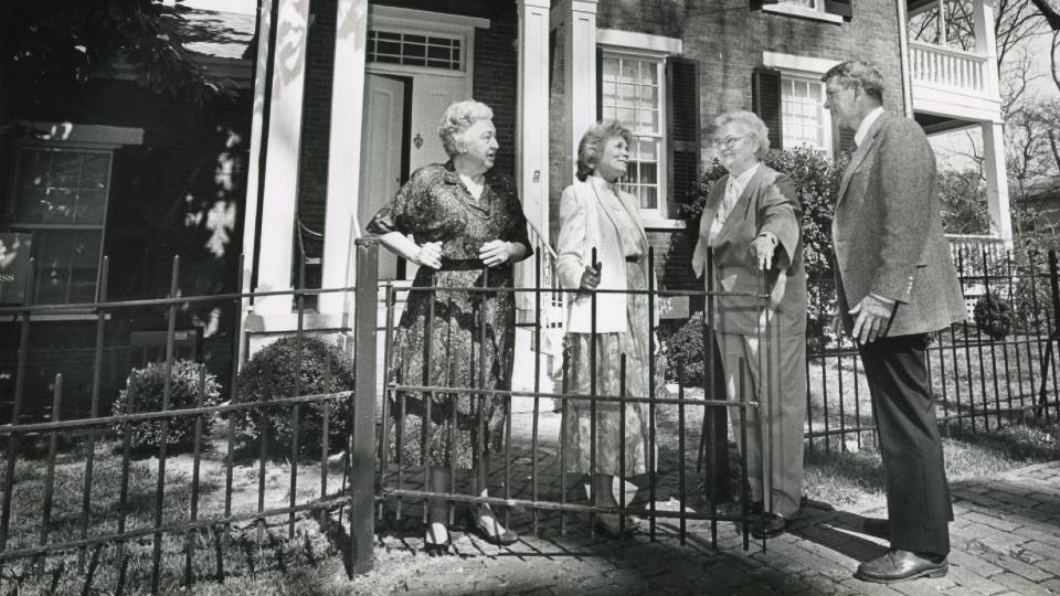 subjects standing around a gated sidewalk in front of the beautiful historic federal-style home of Dr. Roberts