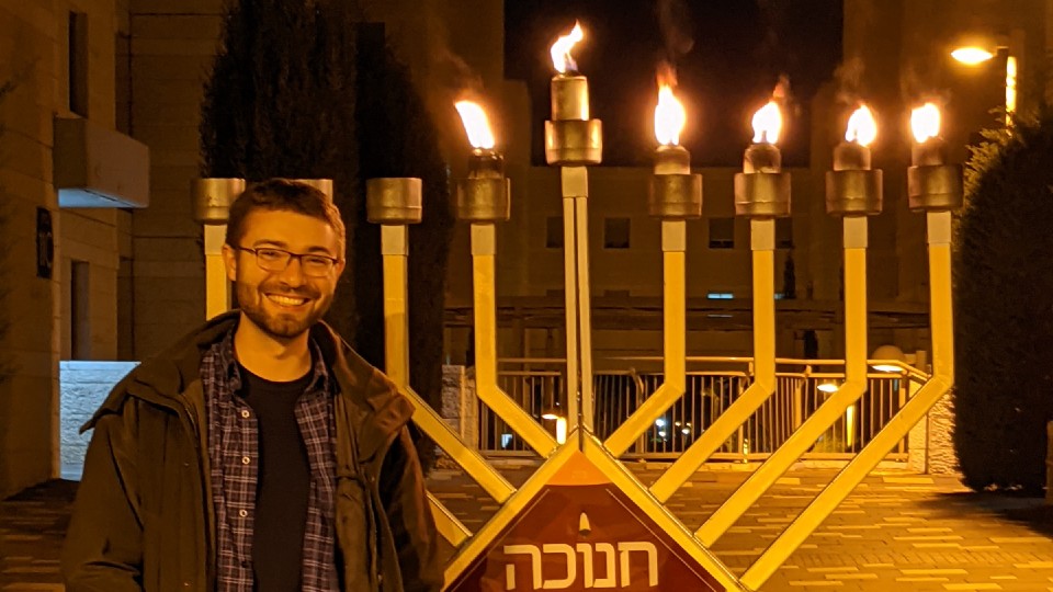 Russel Pope standing next to a large menorah