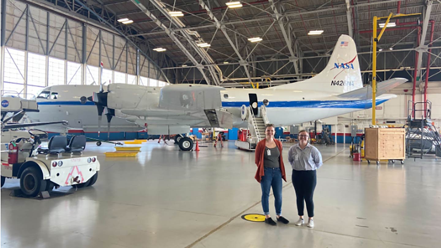 Shelby Bagwell and Ashlyn Shirey stand in front of a P-3 Aircraft