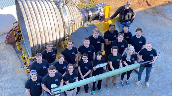Group photo of student team members holding rocket.