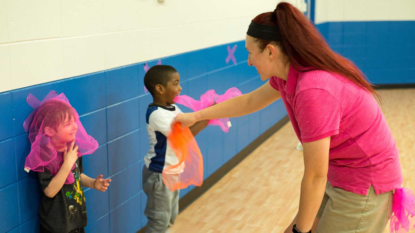 adult woman with two children playing in a gym