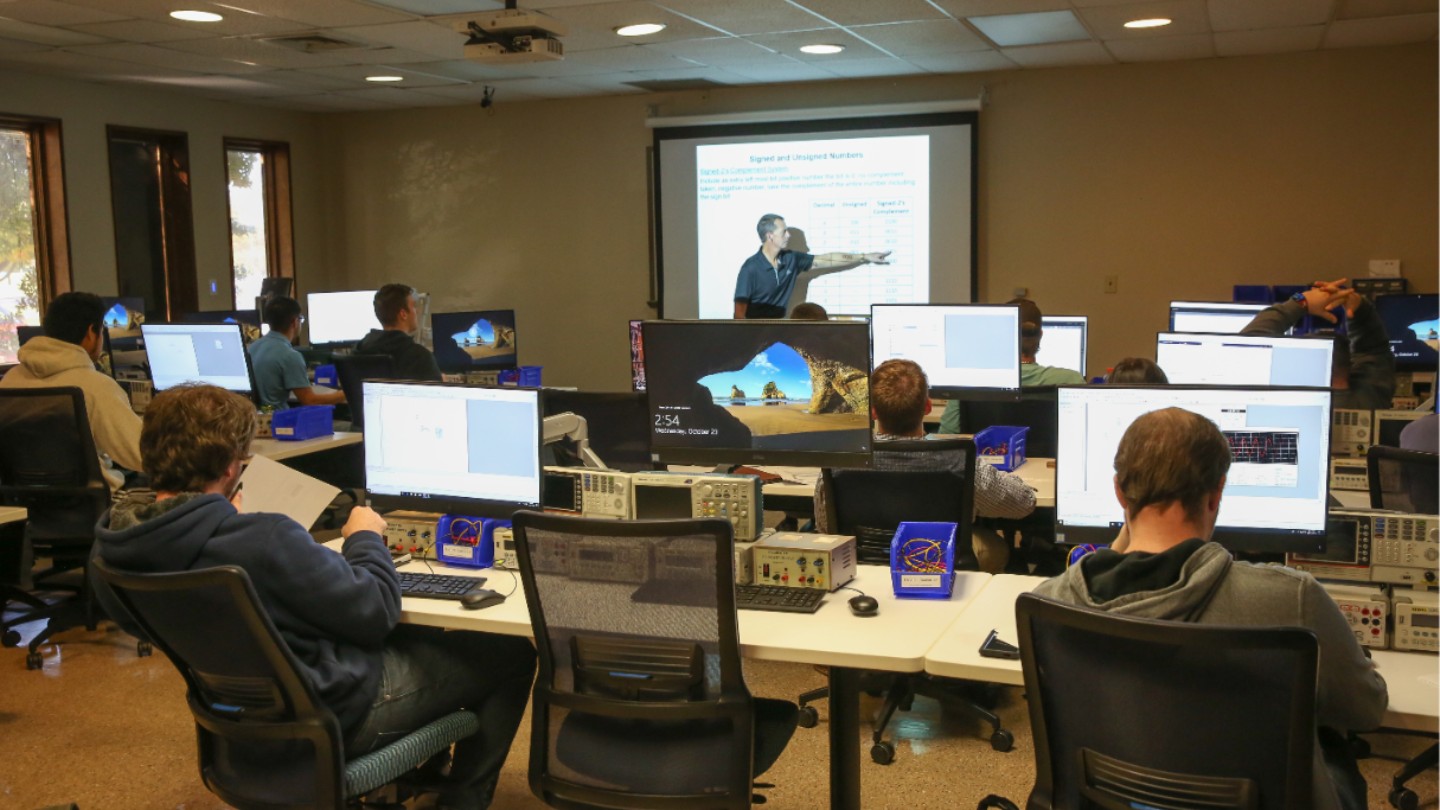 A lecture is given to a class in a computer lab