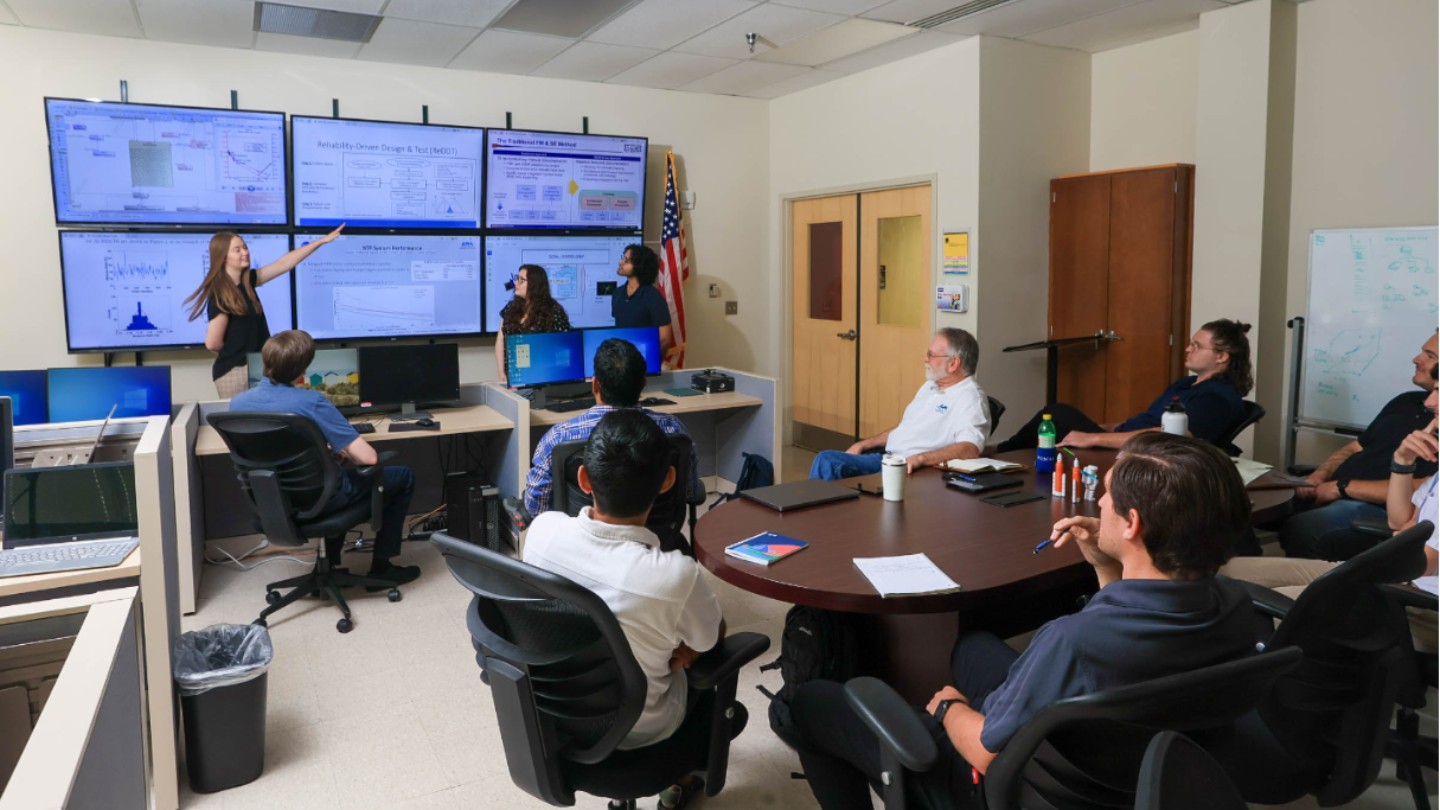 3 Students presenting in the CSIL lab with the screens in the background