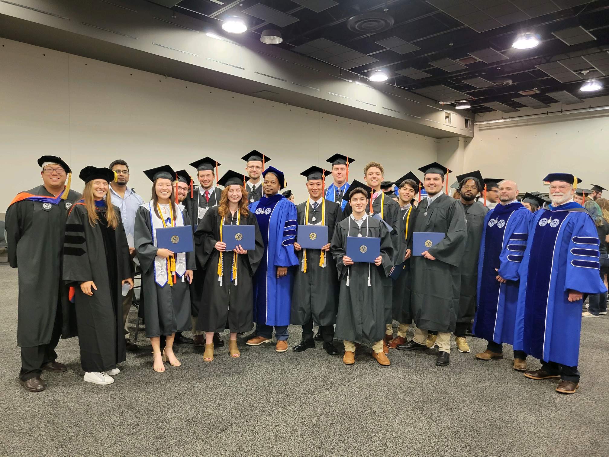 Commencement, group of students and faculty holding diplomas