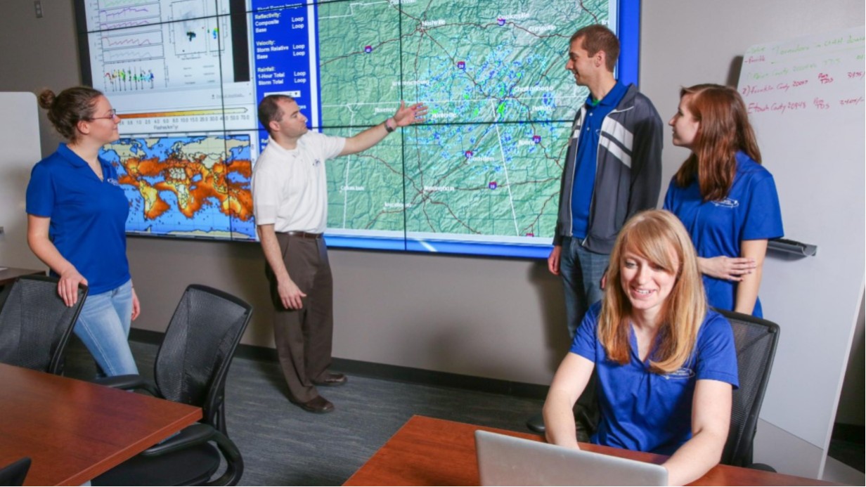 Students in a lab looking at a weather map on a large screen.