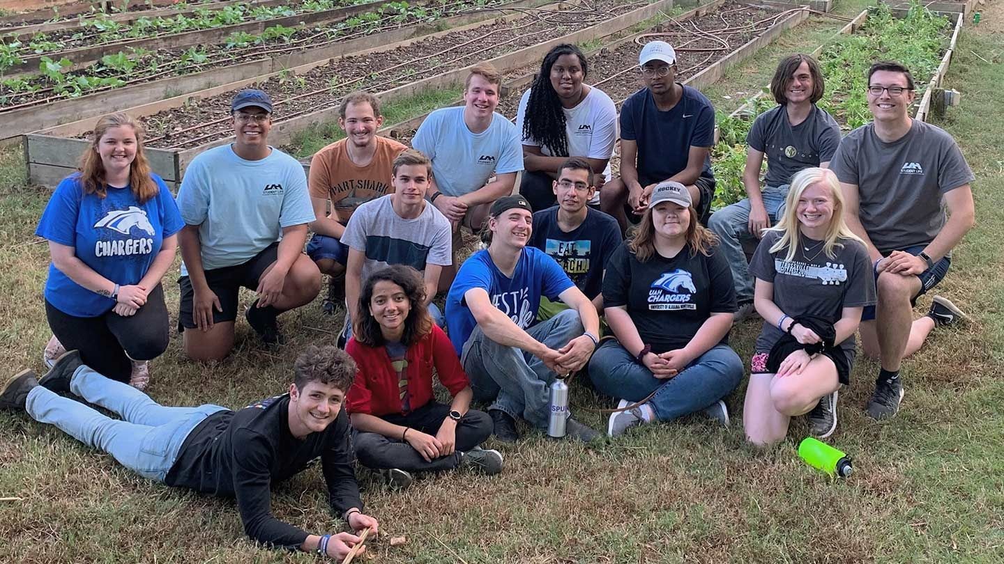 Students posing for a photo with a garden background.