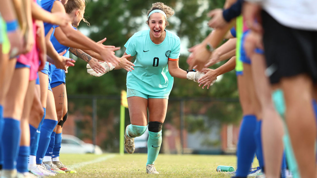 A U A H soccer player runs excitedly through a gauntlet of her supportive teammates before a game.