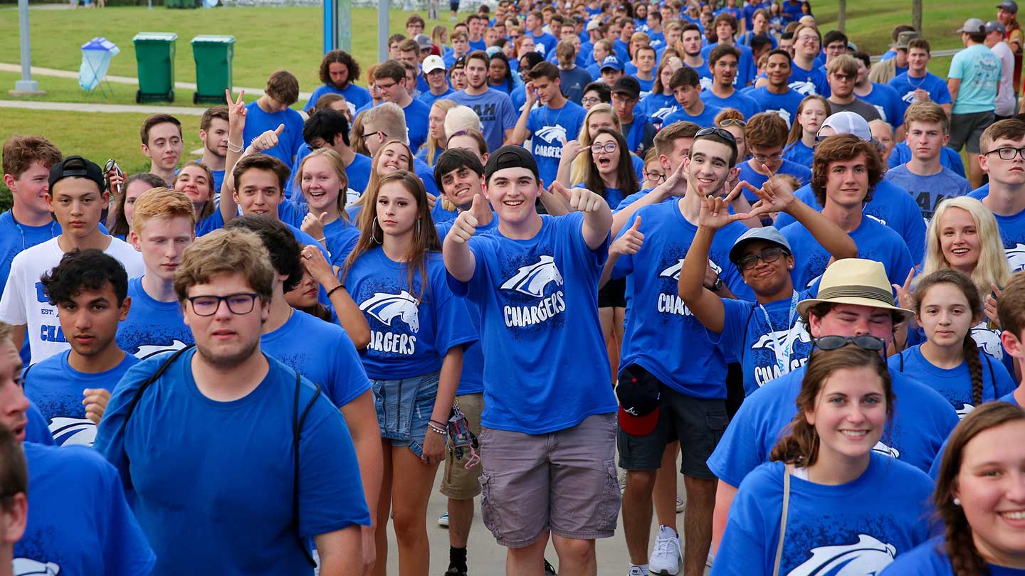 Photo of graduating students walking down university greenway