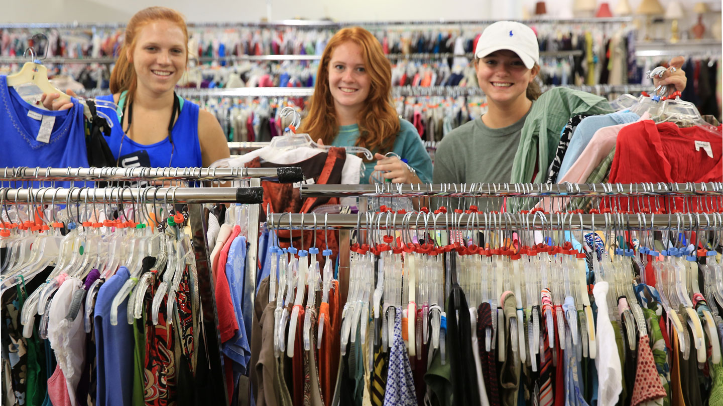 three U A H students organize donated clothing on a series of racks