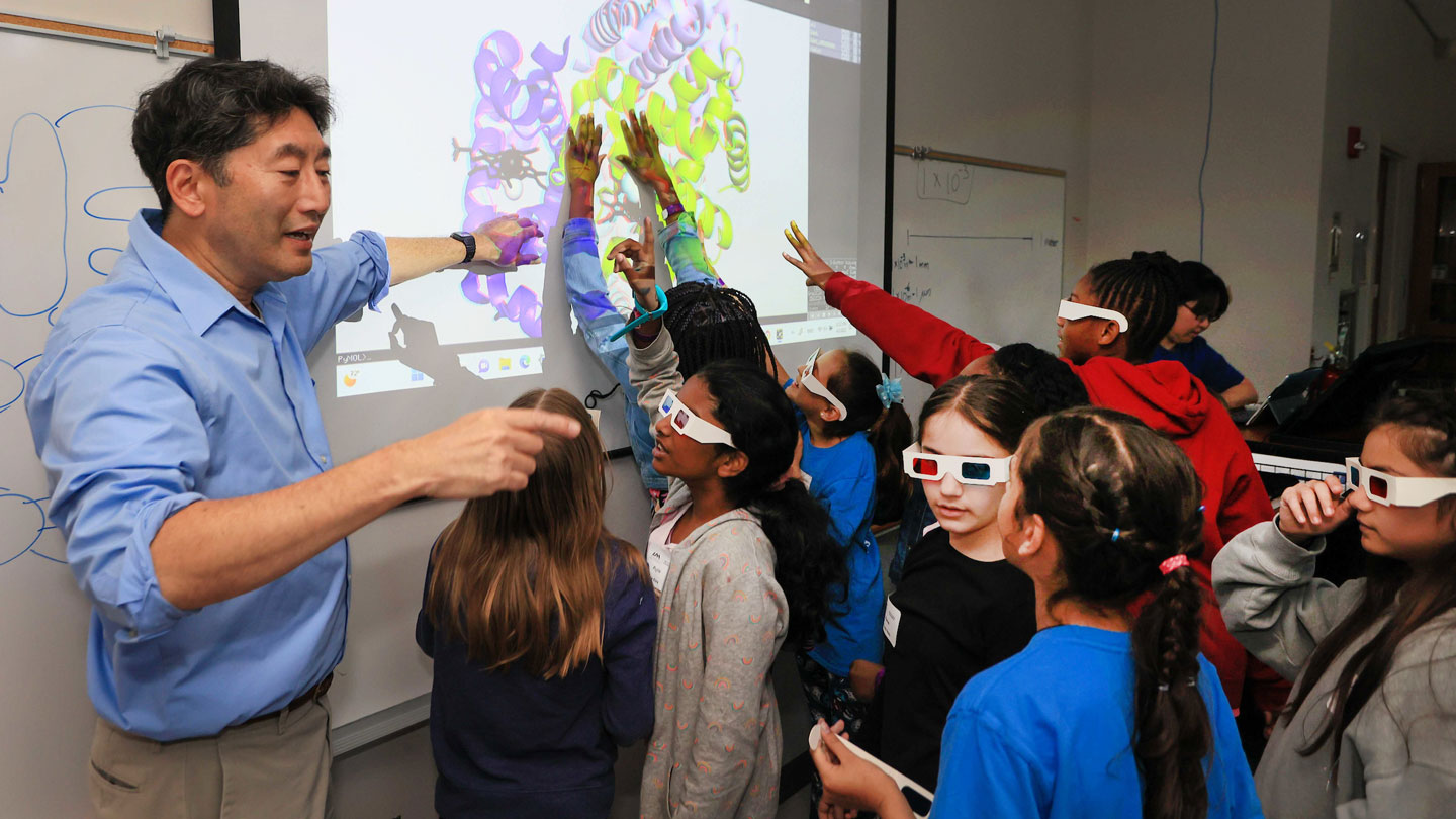 A man gives a presentation on 3D graphics to children with 3D glasses