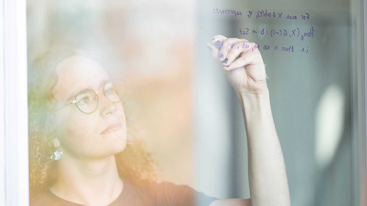 A woman solves math equations on a window