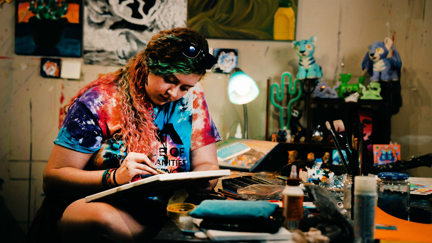An art student sits surrounded by art supplies