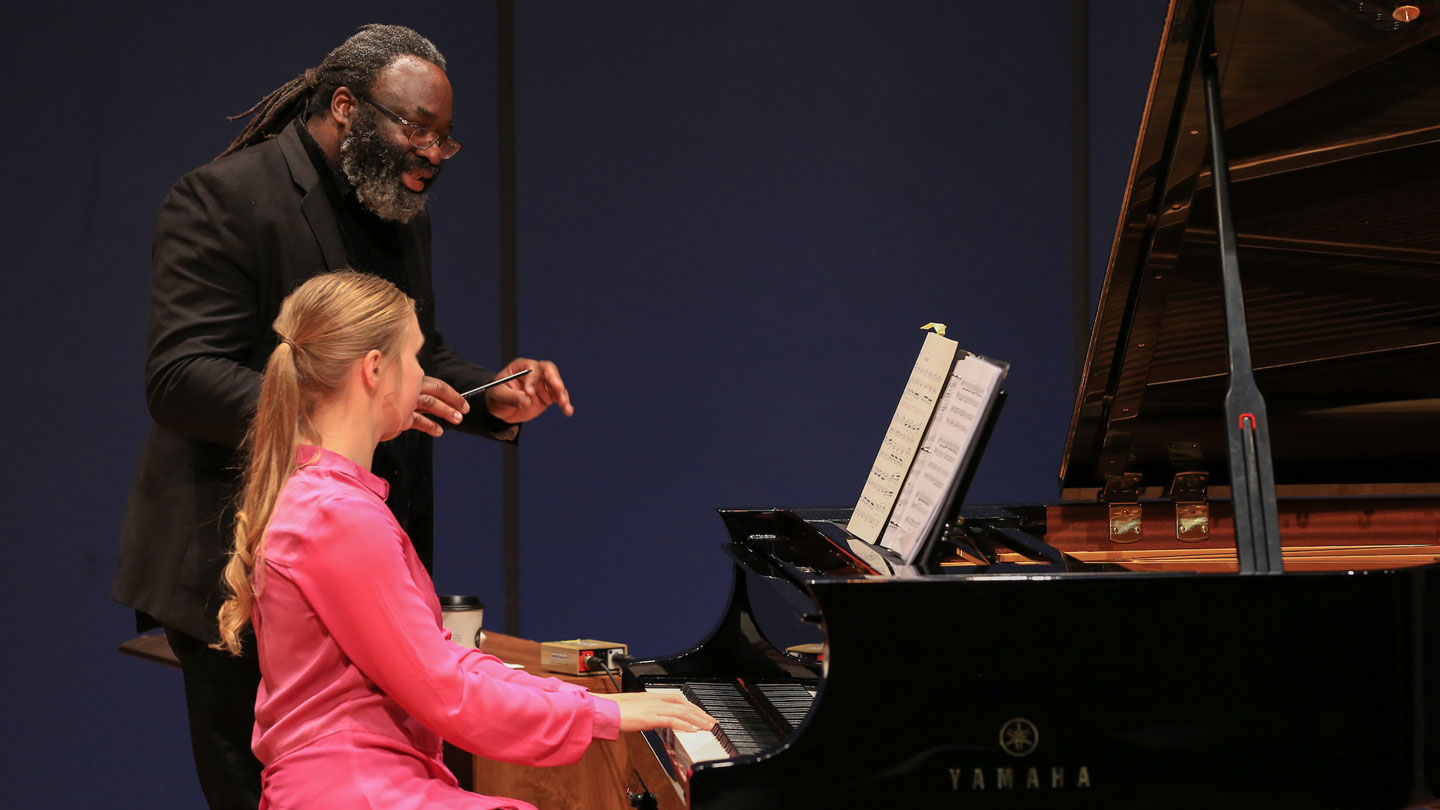 A man expertly teaches piano to a student