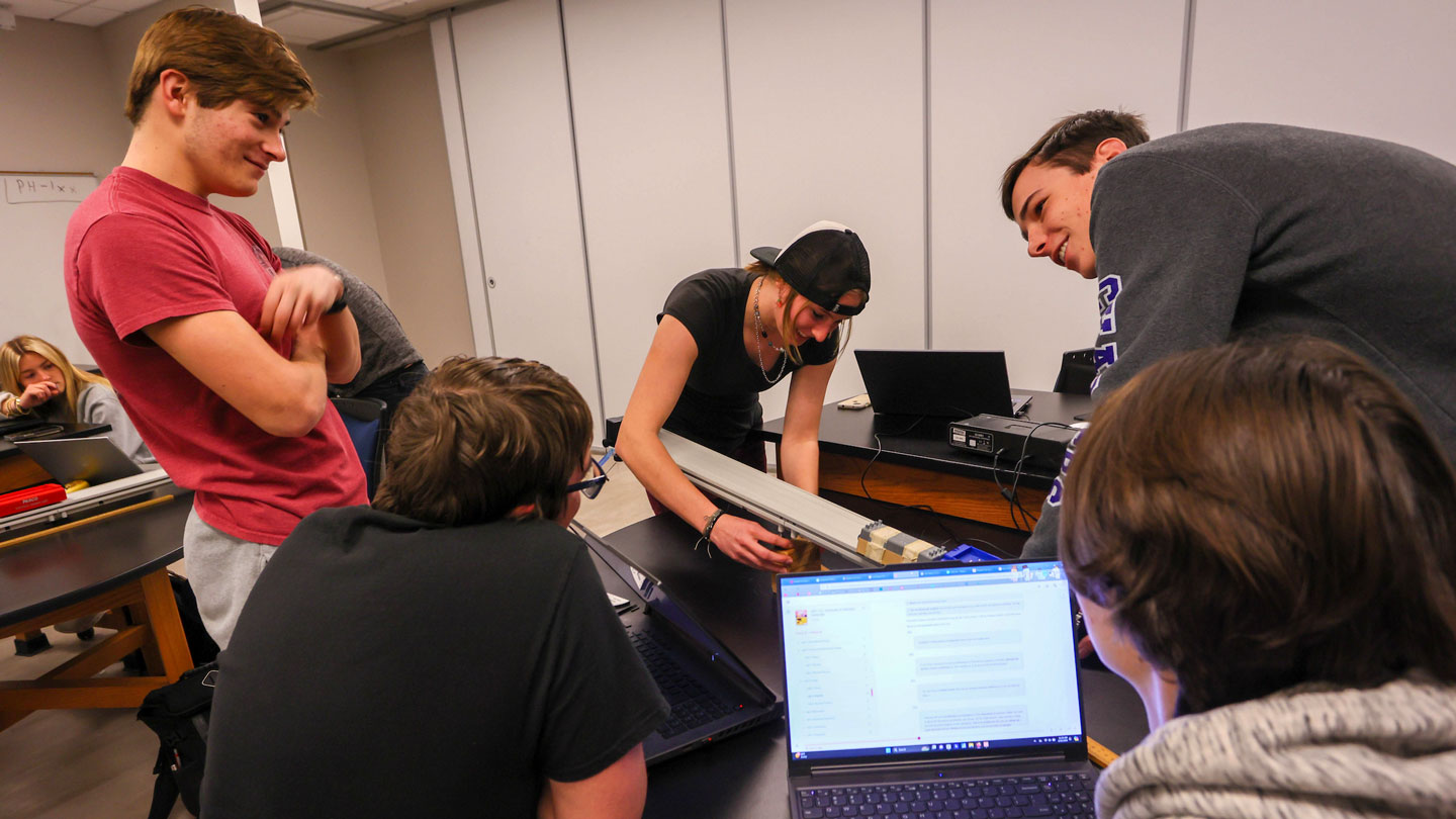 Students smile while working on a group project
