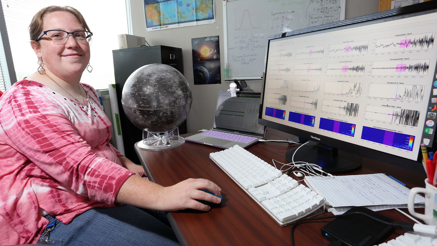 A woman smiles while reading data from a monitor