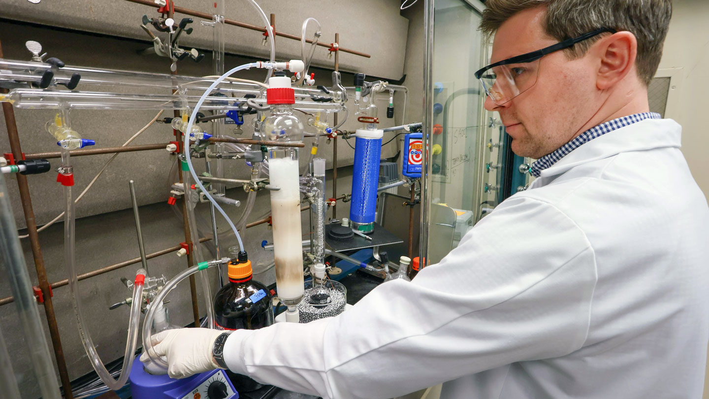 A man uses lab equipment while in a lab coat