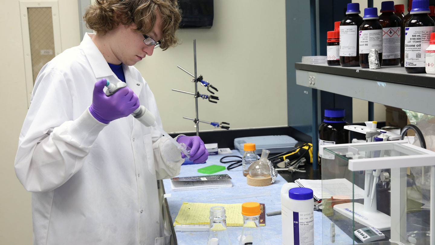 A student carefully transfers materials from one container to another