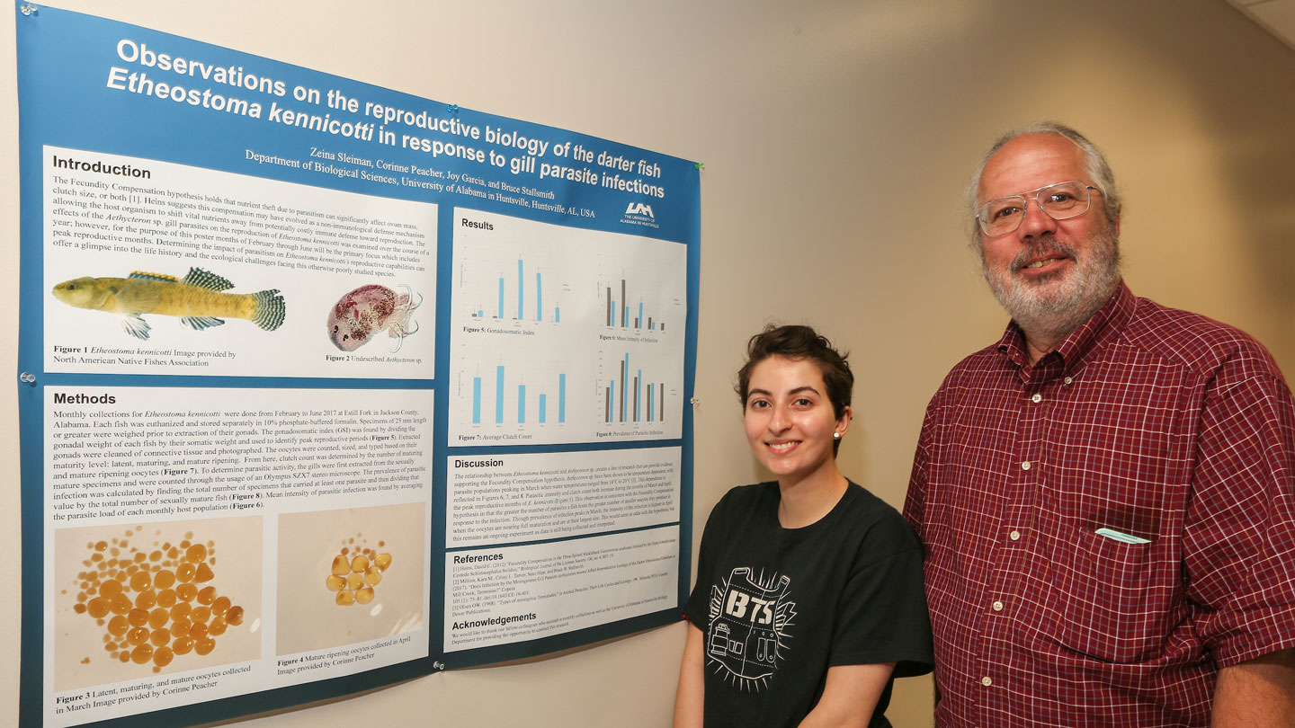 A student stands produly in front of her data presentation board