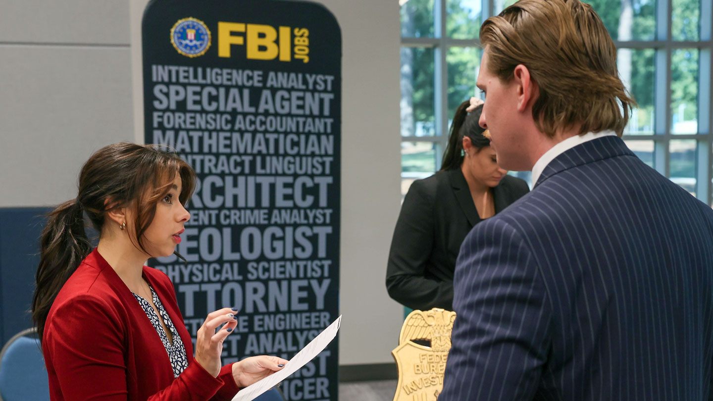 A criminology and intelligence studies student meets with an FBI recruiter at a UAH job fair.
