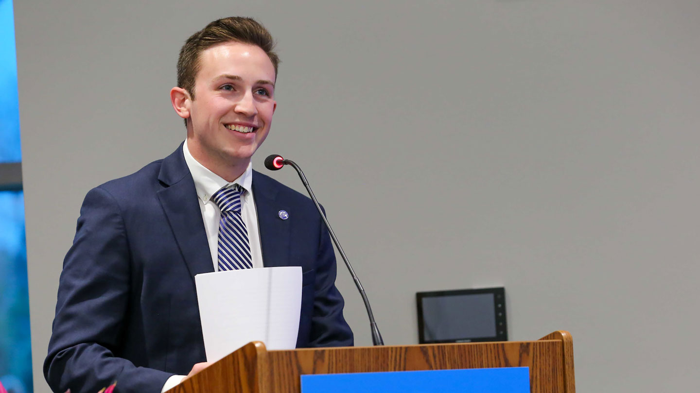 A student in a suit excitedly gives a lecture