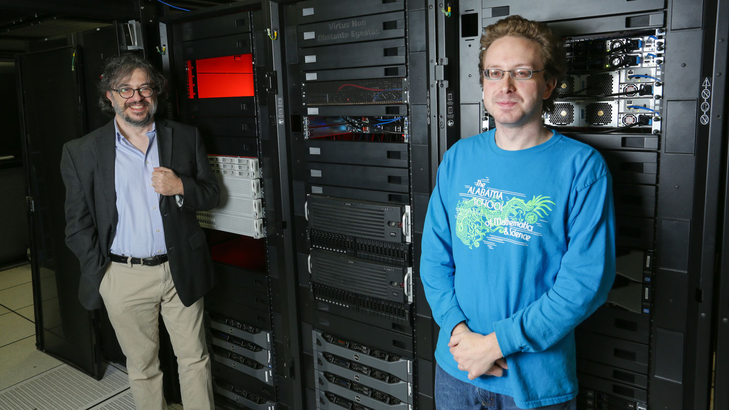 Two people stand in front of server racks