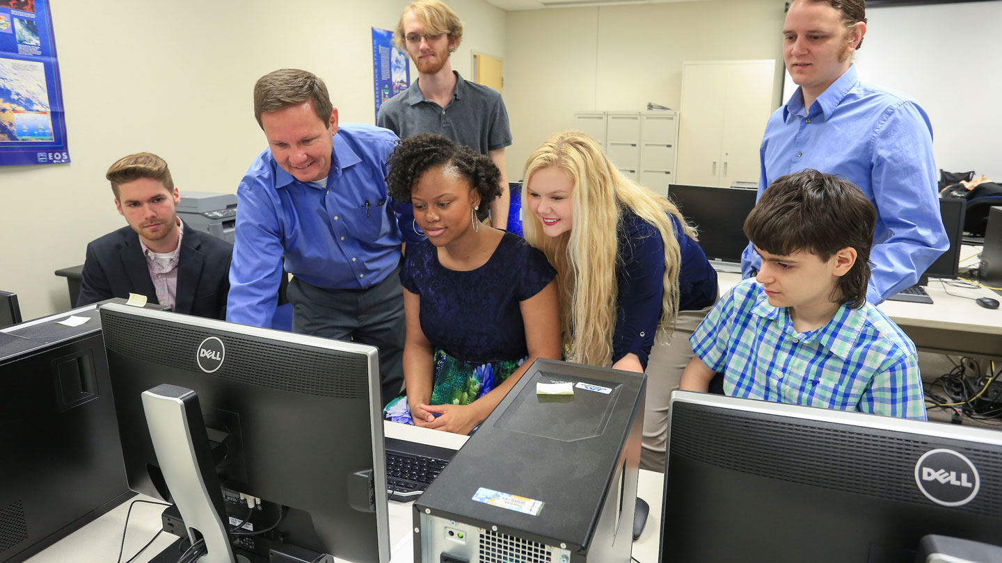 Several people gather around one students computer