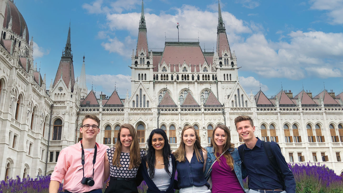 A group of smiling U A H students pose in front of a historic building in Germany.