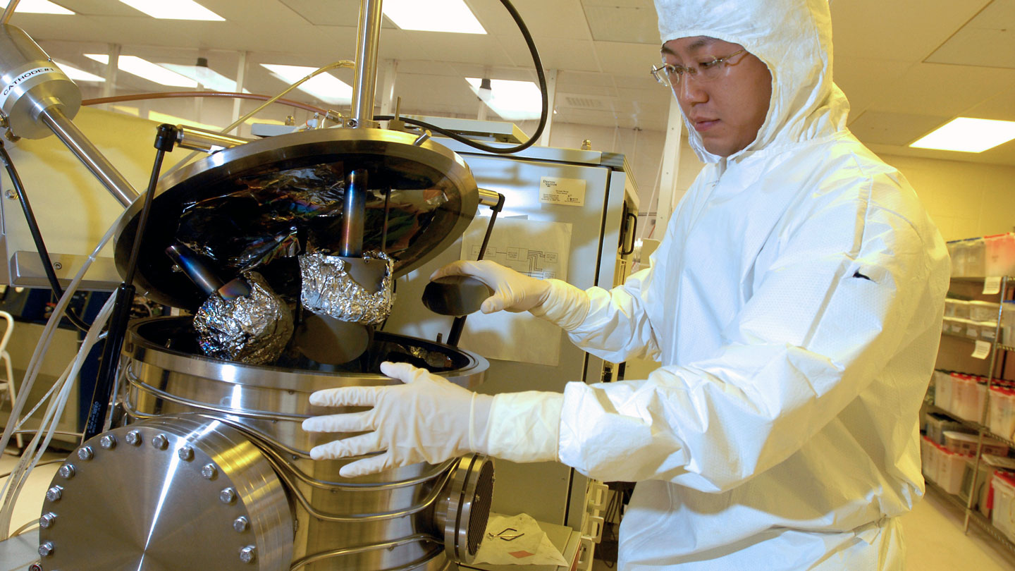 A student uses equipment in a sterile room while wearing sterile gear