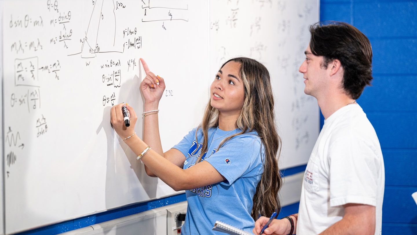 A woman happily shows mathmatics to her peer