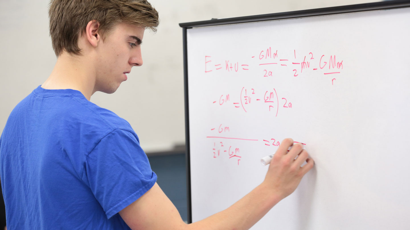 A man writes mathematics onto a whiteboard