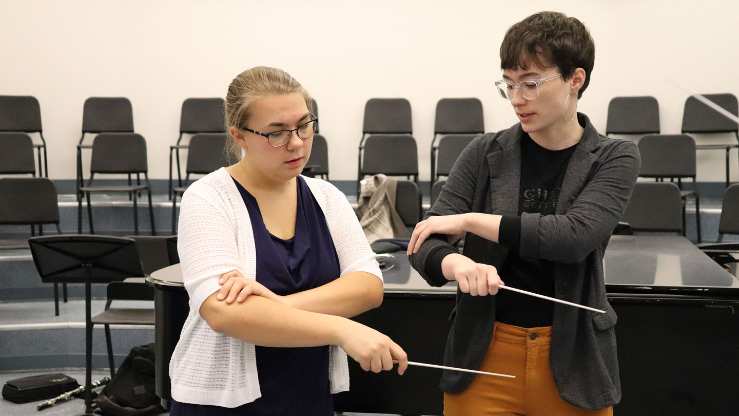 Two people work on musical conducting techniques