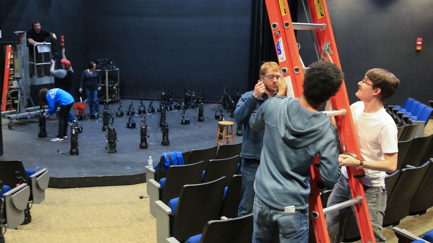 A student stage crew works on the setup for a musical production