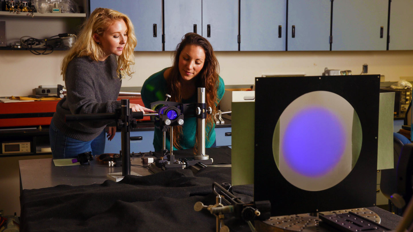 Two women look with interest at optical equipment