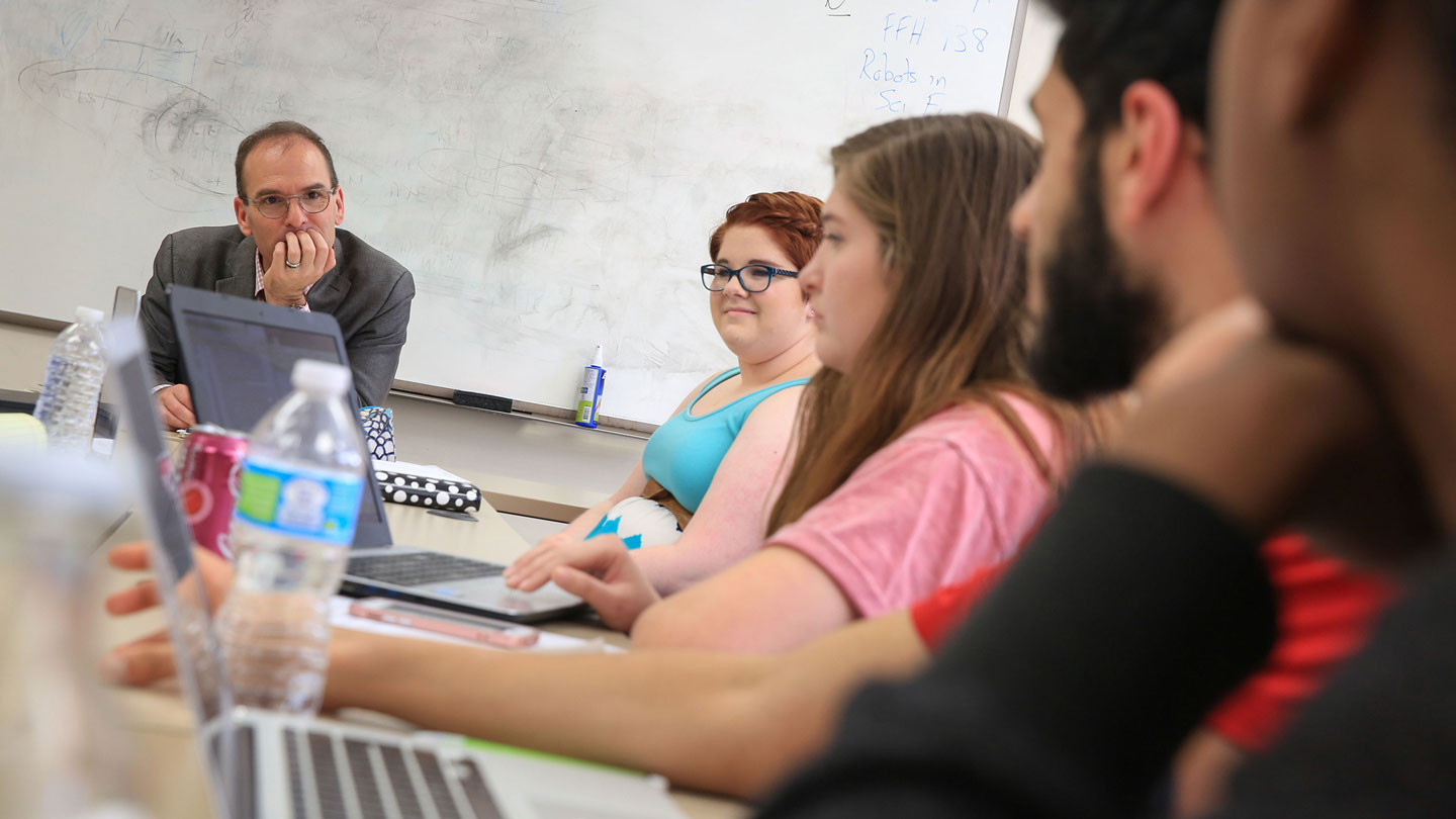 A professor listens to his students input during class