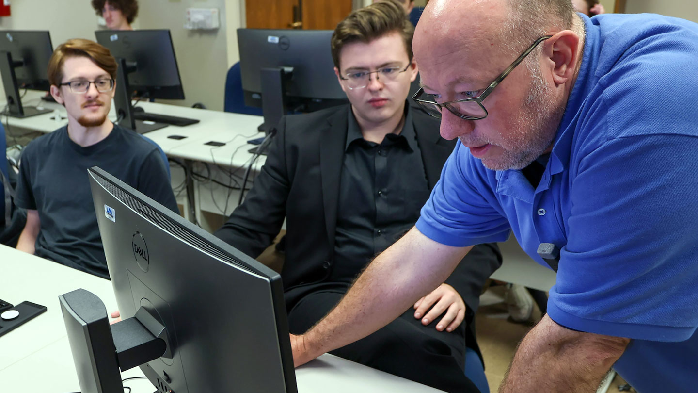 A teacher critques a students work on their computer