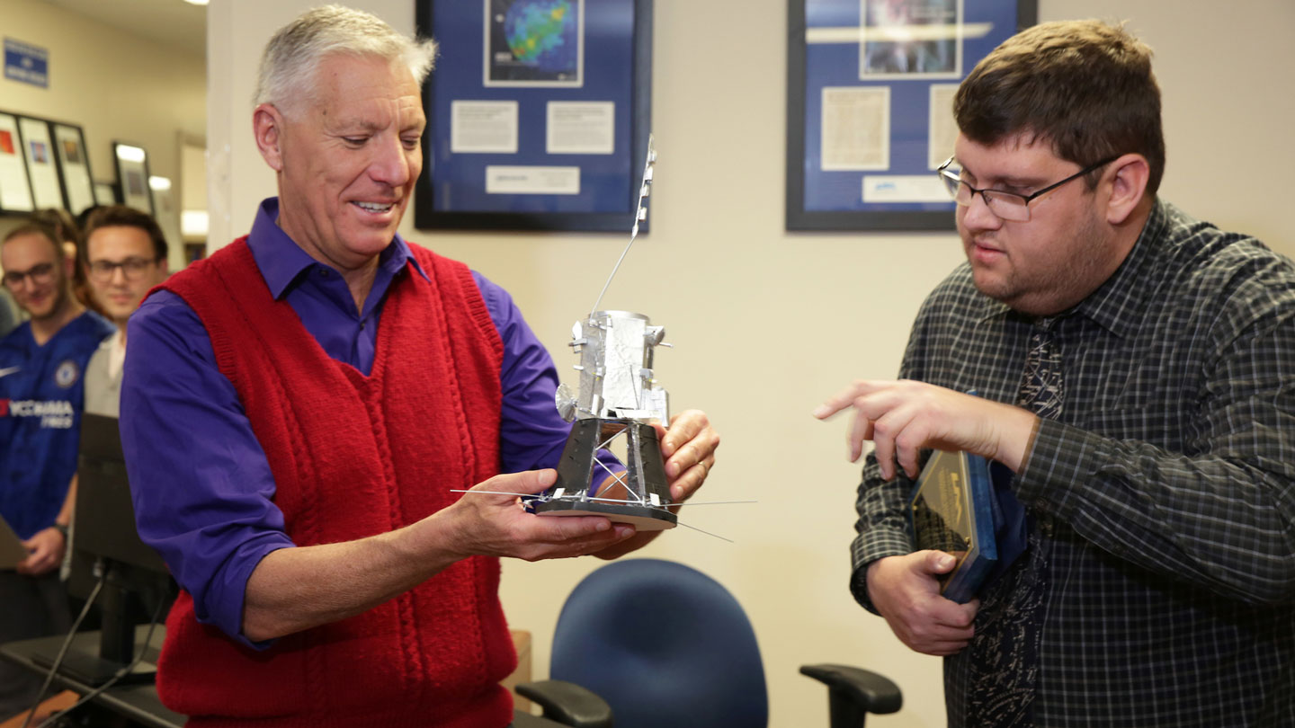 A instructer holds a students model joyfully