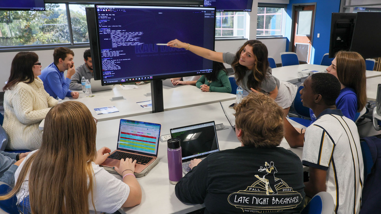 A student points out a line of computer code to her classmates.