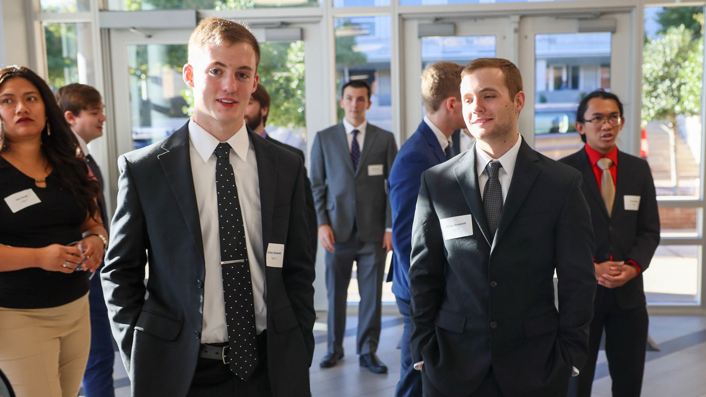 Students gather in a sunlit lobby before dinner etiquette lesson.