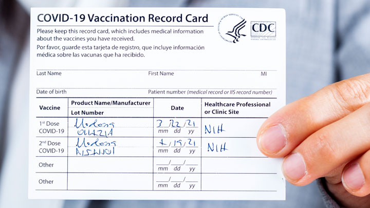 a hand holding a sample CDC vaccination card