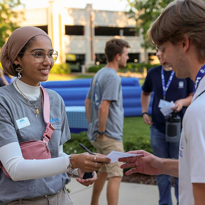 a UAH student passes paper to a potential student