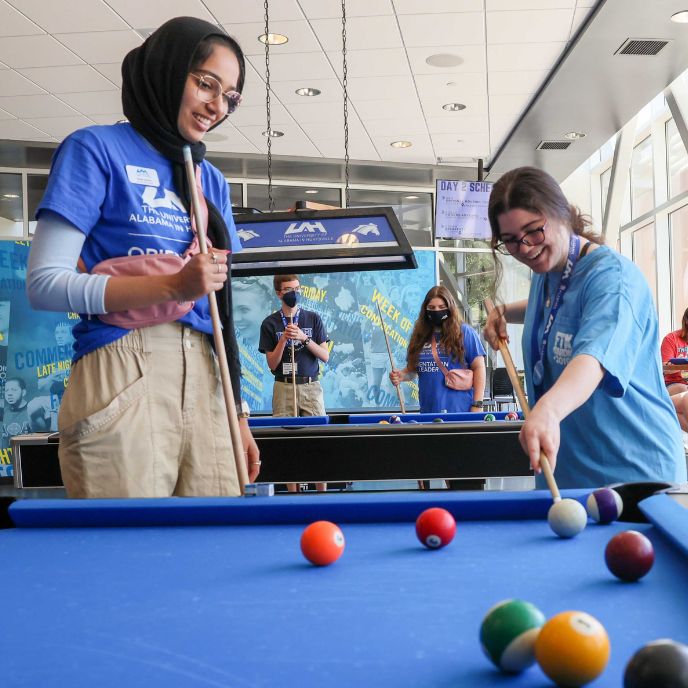 a UAH student plays pool with an incoming freshman