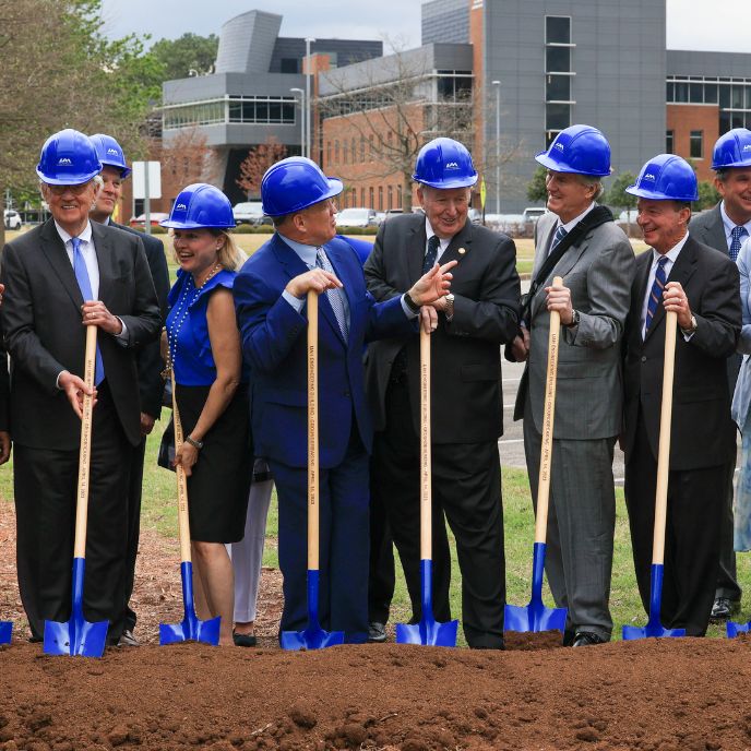 a group of people in blue safety helmets wielding shovels