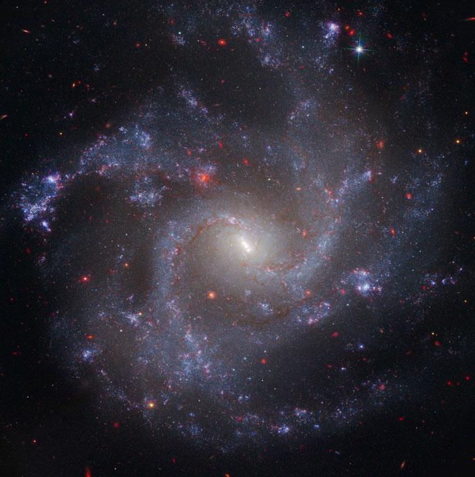 A vibrant spiral galaxy featuring bright blue star clusters and a central yellowish core, set against a dark cosmic background.