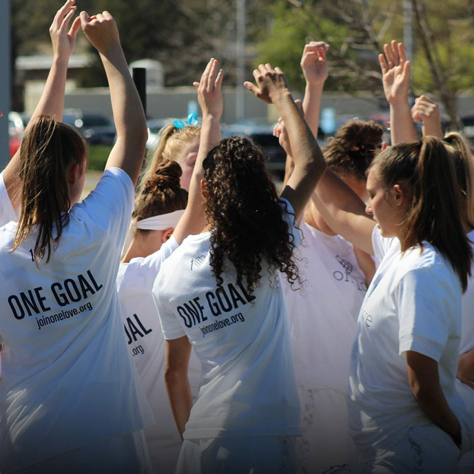 the UAH women's lacrosse team celebrates in a huddle with fists raised above their heads